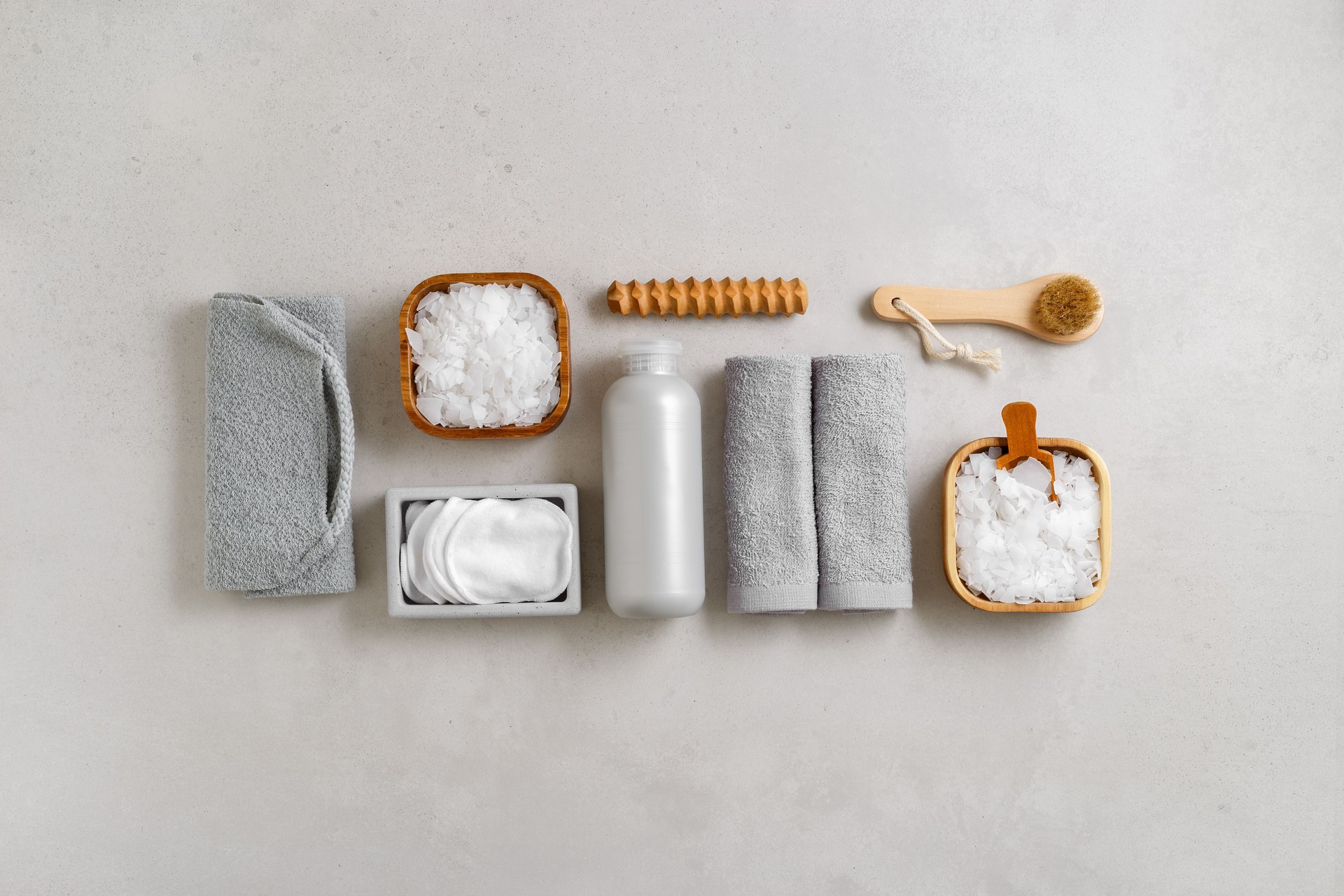 Top view Spa or bath accessories on grey background. Sea salt, cotton towels, natural brushes, wooden massagers, washcloth, relaxation, self-care routines, or eco-friendly beauty products, above
